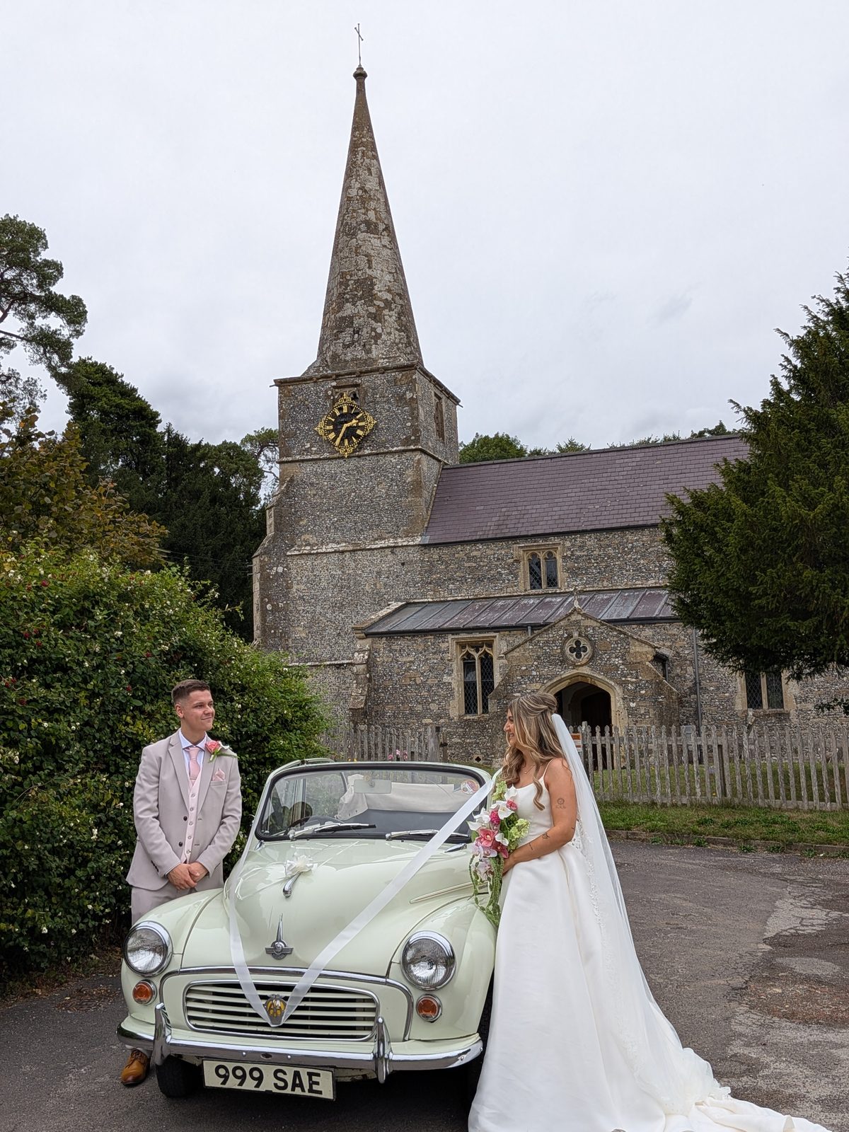 Bride and groom with Annie the Morris Minor wedding car outside church, Wiltshire